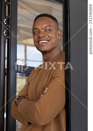 African american man leaning by glass partition frame in modern office wearing wristwatch African american man leaning by glass partition frame in modern office wearing wristwatch 141540809