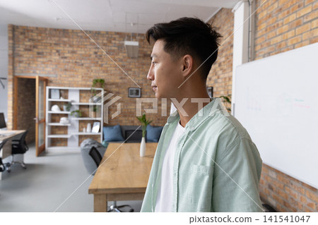 Asian man standing in coworking conference room meeting table and whiteboard, copy space 141541047