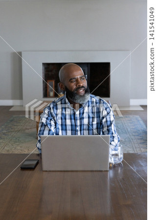 Senior african american man working on laptop with smartphone in living room at table 141541049