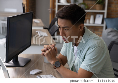 Asian man typing on keyboard with ceramic mug at desk in office workspace, copy space Asian man typing on keyboard with ceramic mug at desk in office workspace, copy space 141541050