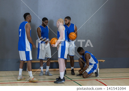 African american male teammates with basketballs standing by bench on court discussing strategy African american male teammates with basketballs standing by bench on court discussing strategy 141541094