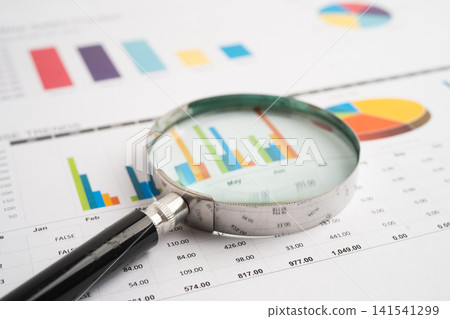 Magnifying glass on spreadsheet and graph paper. Financial data economy, Business. Magnifying glass on spreadsheet and graph paper. Financial data economy, Business. 141541299