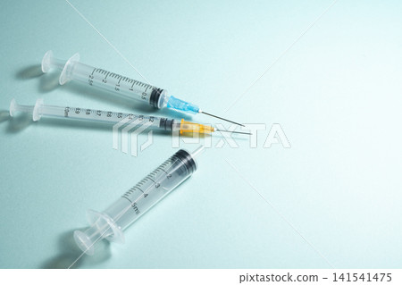 Syringes and medical equipment lined up against a light blue background. 141541475