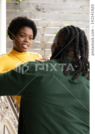 African american friends sitting on decorative patio chairs in backyard sipping from mugs African american friends sitting on decorative patio chairs in backyard sipping from mugs 141541920