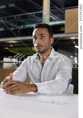 Man working at white table in office wearing button-up shirt and using usb power hub Man working at white table in office wearing button-up shirt and using usb power hub 141541982