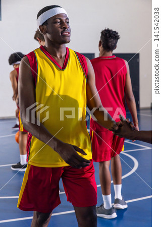 African american teenage basketball players high-fiving on blue court with basketball African american teenage basketball players high-fiving on blue court with basketball 141542038