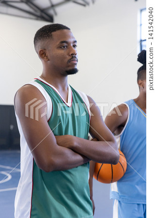 African american teammates wearing jerseys, holding basketball in gym, copy space 141542040