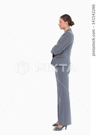 Woman in mid 30s standing with arms crossed in studio wearing tailored grey pantsuit, copy space Woman in mid 30s standing with arms crossed in studio wearing tailored grey pantsuit, copy space 141542266