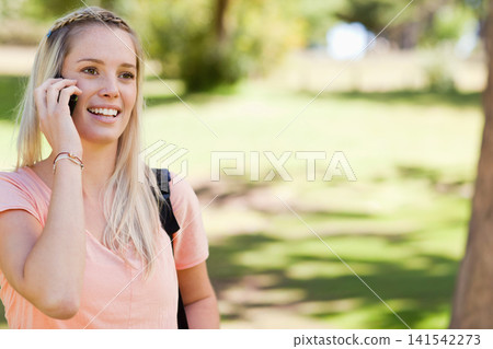 Woman standing in park talking on phone, smiling in peach shirt with black backpack, copy space Woman standing in park talking on phone, smiling in peach shirt with black backpack, copy space 141542273