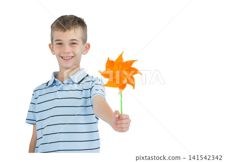 Child in light blue polo, smiling, holding orange pinwheel on green stick at studio, copy space 141542342
