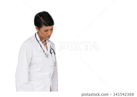 Mature female doctor standing looking down on white wall in white lab coat, stethoscope, copy space 141542389