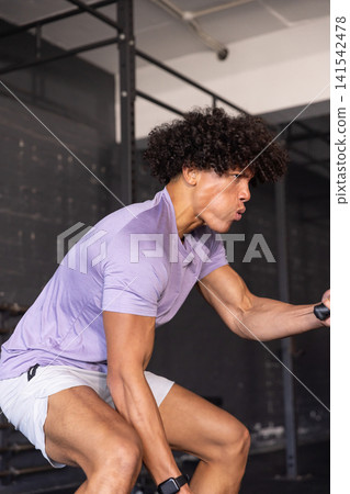 African american adult male gripping cable handle performing row in gym with smartwatch African american adult male gripping cable handle performing row in gym with smartwatch 141542478