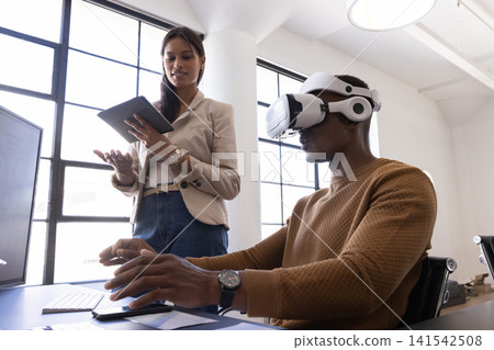 Diverse coworkers collaborating on virtual reality project, using headset keyboard tablet Diverse coworkers collaborating on virtual reality project, using headset keyboard tablet 141542508