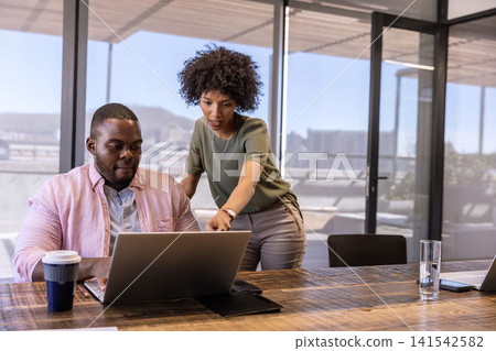 African american coworkers collaborating over laptop with coffee cup in office African american coworkers collaborating over laptop with coffee cup in office 141542582