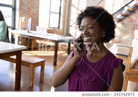 African american coworkers talking on smartphone, working on laptop in office African american coworkers talking on smartphone, working on laptop in office 141542673