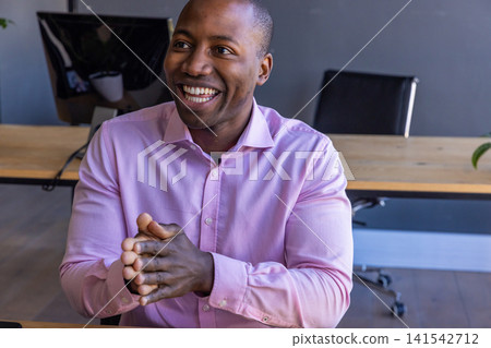African american man wearing pink dress shirt, listening attentively at desk with monitor African american man wearing pink dress shirt, listening attentively at desk with monitor 141542712