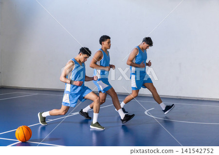 African american teenage athlete lunging on basketball court with white lines and basketball African american teenage athlete lunging on basketball court with white lines and basketball 141542752