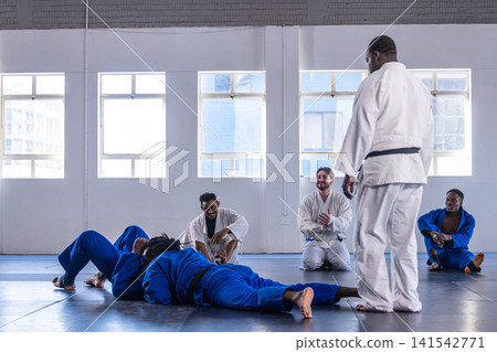 Diverse martial class with instructor practicing sparring in gis on mats in studio, copy space 141542771