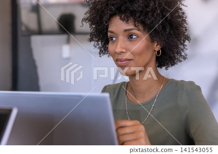 African american woman typing on laptop at desk, viewing monitor, copy space African american woman typing on laptop at desk, viewing monitor, copy space 141543055