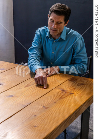 Middle-aged man wearing teal button-down shirt pointing at table grain in office, copy space Middle-aged man wearing teal button-down shirt pointing at table grain in office, copy space 141543210