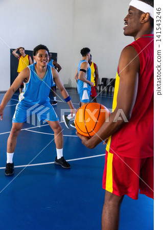 African american teen male in blue uniform guarding opponent holding orange ball on court African american teen male in blue uniform guarding opponent holding orange ball on court 141543246