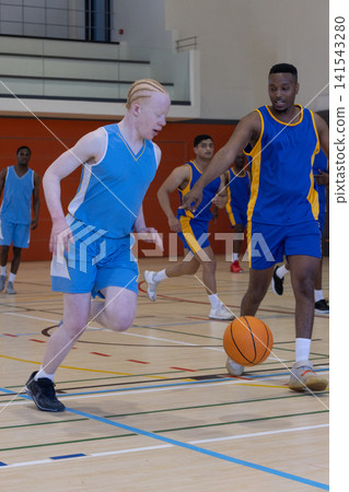 Diverse male basketball players wearing uniforms dribbling ball on basketball court Diverse male basketball players wearing uniforms dribbling ball on basketball court 141543280