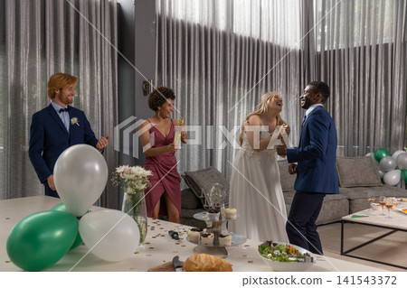 Diverse couple dancing and laughing in decorated reception hall with balloons, cupcake stand Diverse couple dancing and laughing in decorated reception hall with balloons, cupcake stand 141543372