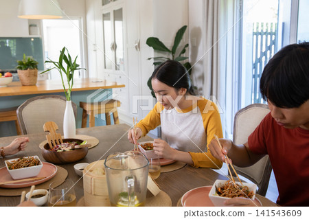 Asian couple eating noodles at home dining table with steamer basket and chopsticks 141543609