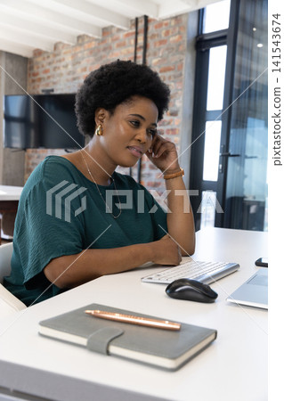 Mid adult african american woman using silver laptop and wireless keyboard at office desk Mid adult african american woman using silver laptop and wireless keyboard at office desk 141543674