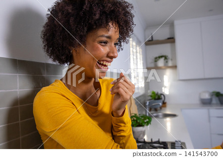 African american woman leaning on backsplash and laughing in kitchen, copy space African american woman leaning on backsplash and laughing in kitchen, copy space 141543700