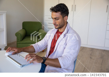 Man typing on wireless keyboard and moving mouse on round table at home office Man typing on wireless keyboard and moving mouse on round table at home office 141543701