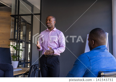 African american male colleagues presenting ideas in office meeting room with laptop, flip chart African american male colleagues presenting ideas in office meeting room with laptop, flip chart 141543731