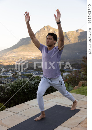 African american man practicing yoga lunge on tiled terrace with yoga mat and fitness tracker African american man practicing yoga lunge on tiled terrace with yoga mat and fitness tracker 141543740
