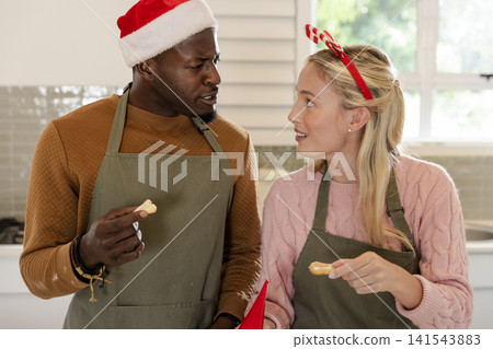 Diverse couple chatting while decorating holiday cookies on modern kitchen countertop Diverse couple chatting while decorating holiday cookies on modern kitchen countertop 141543883