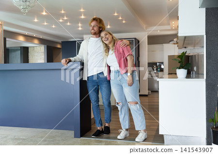 Couple smiling and leaning behind navy blue kitchen island in open kitchen 141543907