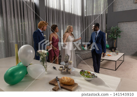 Diverse wedding party in formal wear gathering at reception with balloons, dessert stand Diverse wedding party in formal wear gathering at reception with balloons, dessert stand 141543910