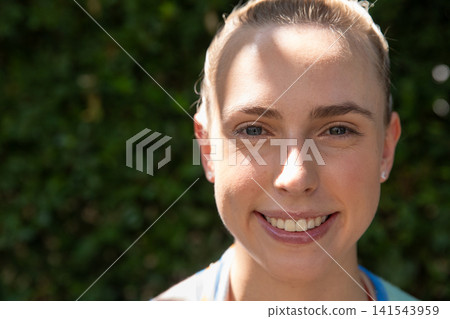 Woman smiling while standing in garden in athletic top with headband stud earrings, copy space Woman smiling while standing in garden in athletic top with headband stud earrings, copy space 141543959
