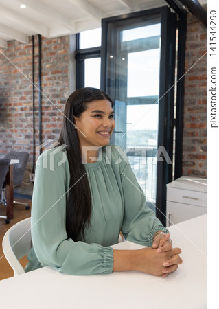 African american woman sitting at desk in office, facing glass windows, engaging meeting African american woman sitting at desk in office, facing glass windows, engaging meeting 141544290