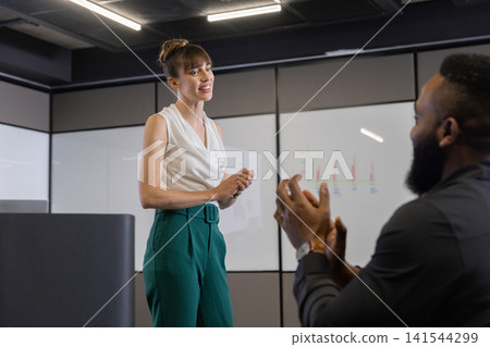 Diverse coworkers presenting bar chart on whiteboard in conference room in formal attire 141544299