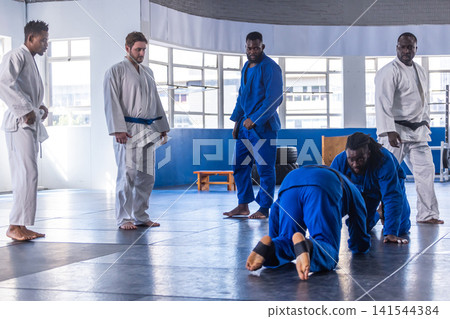 African american male martial artists grappling in dojo with padded mats and gis, copy space 141544384