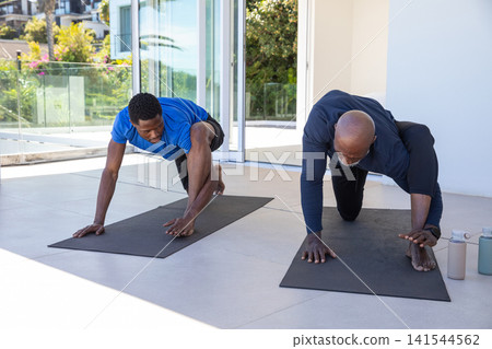 African american father and son practicing yoga lunges on tiled terrace with black mats African american father and son practicing yoga lunges on tiled terrace with black mats 141544562