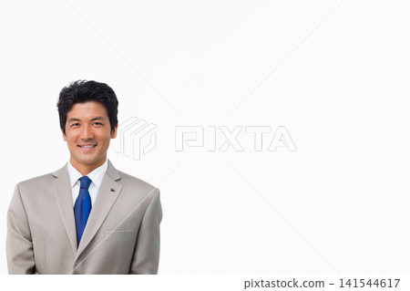 Mid-adult Asian man standing left on white backdrop, wearing gray suit blue tie, pin, copy space Mid-adult Asian man standing left on white backdrop, wearing gray suit blue tie, pin, copy space 141544617