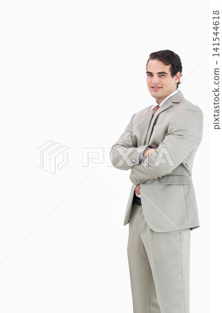 Adult man standing arms crossed in studio wearing light gray suit, brown tie, copy space Adult man standing arms crossed in studio wearing light gray suit, brown tie, copy space 141544618