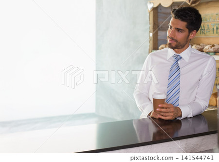 Man in shirt and tie leaning at counter holding takeaway cup, shelves with loaves, copy space 141544741