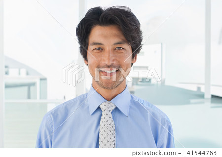 Mid-adult Asian man smiling and standing in corporate office wearing blue shirt and patterned tie Mid-adult Asian man smiling and standing in corporate office wearing blue shirt and patterned tie 141544763