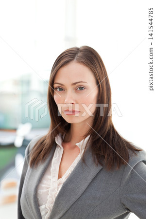 Female posing, facing camera in office with backlit window, wearing gray blazer and ruffled blouse Female posing, facing camera in office with backlit window, wearing gray blazer and ruffled blouse 141544785