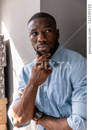 African american man at office, wearing shirt and checking wristwatch next to cardboard boxes African american man at office, wearing shirt and checking wristwatch next to cardboard boxes 141545310
