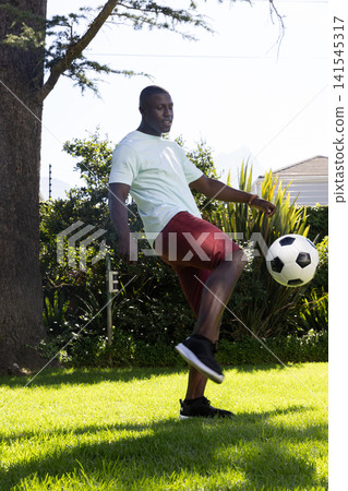 African american man juggling soccer ball in backyard African american man juggling soccer ball in backyard 141545317