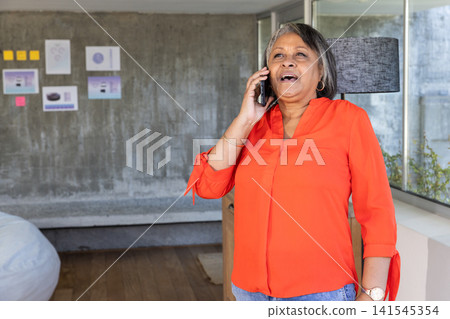 Senior african american woman using smartphone in office with mockups, notes, copy space Senior african american woman using smartphone in office with mockups, notes, copy space 141545354