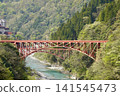 A red iron bridge crossing a gorge 141545473